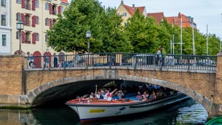 Turyści w czasie wycieczki na łódce przepływają pod mostem, Kopenhaga, Dania